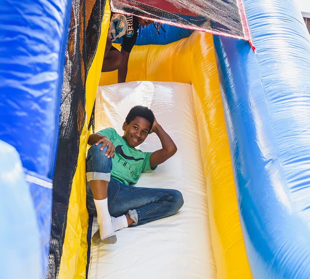 A child posing for the camera as they go down an inflatable slide